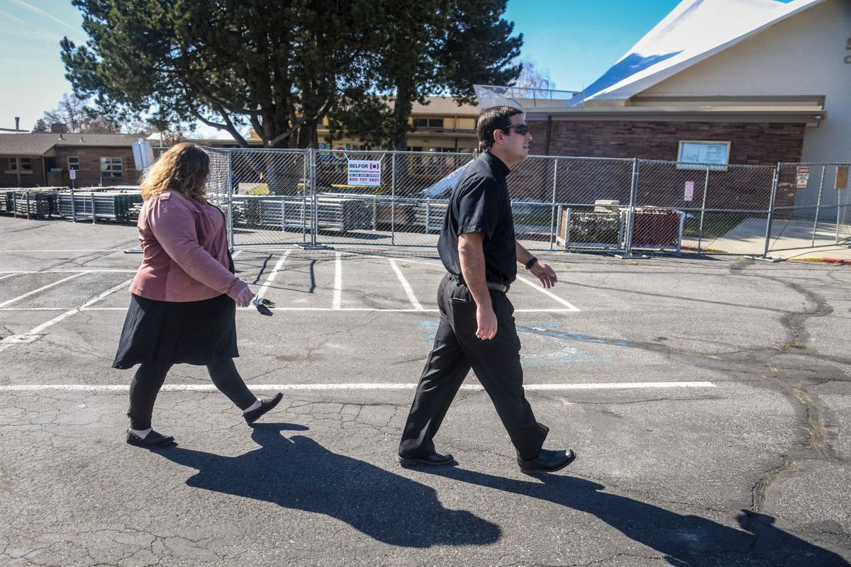 St. Charles Catholic School Principal Heather Schlaich and Rev. Esteban Soler walk past the fire-damaged school, Wednesday, March 30, 2021. The fire was arson caused on March 18.  (DAN PELLE/THE SPOKESMAN-REVIEW)