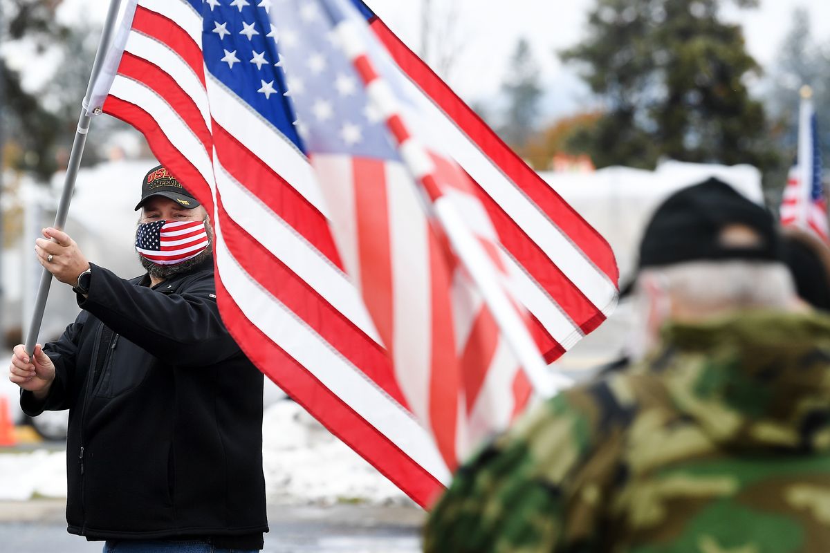 USMC vet Mathew Howard, with Discipled Veteran, Church for Veterans, waves an American Flag during a drive-thru Veterans Day celebration on Wednesday at the Mann-Grandstaff Veterans Administration Medical Center.  (Tyler Tjomsland/THE SPOKESMAN-REVIEW)