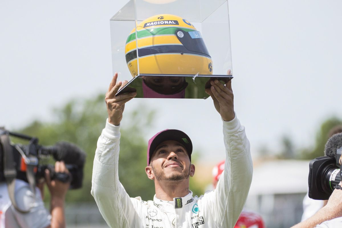 Mercedes driver Lewis Hamilton, of Great Britain, holds up a racing helmet of former F1 driver Ayrton Senna after winning pole position at the F1 Canadian Grand Prix auto race, Saturday, June 10, 2017, in Montreal. (Graham Hughes / Canadian Press via AP)