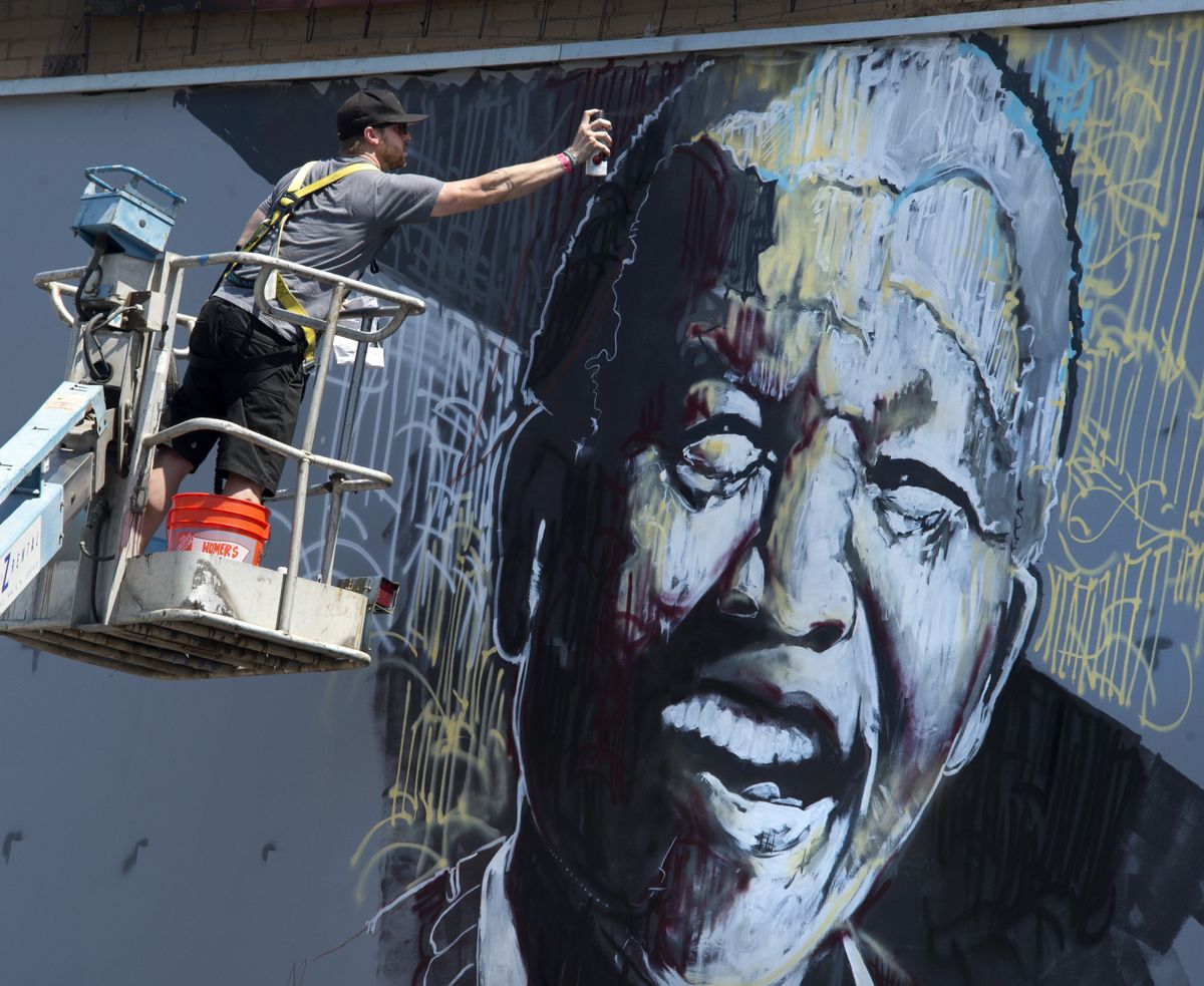 Jessie Pierpoint adds finishing touches Friday to his image of Nelson Mandela on a billboard near Main Avenue and Bernard Street in Spokane. Pierpoint conducted the live painting for Global Credit Union’s Global Citizen Campaign. (Dan Pelle)