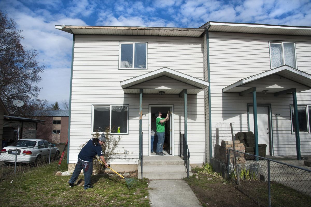 Josh Track rakes the yard as Malaki Ramey caulks the door jambs while working for YouthBuild on the Habitat for Humanity house on East Mallon. (Dan Pelle / The Spokesman-Review)