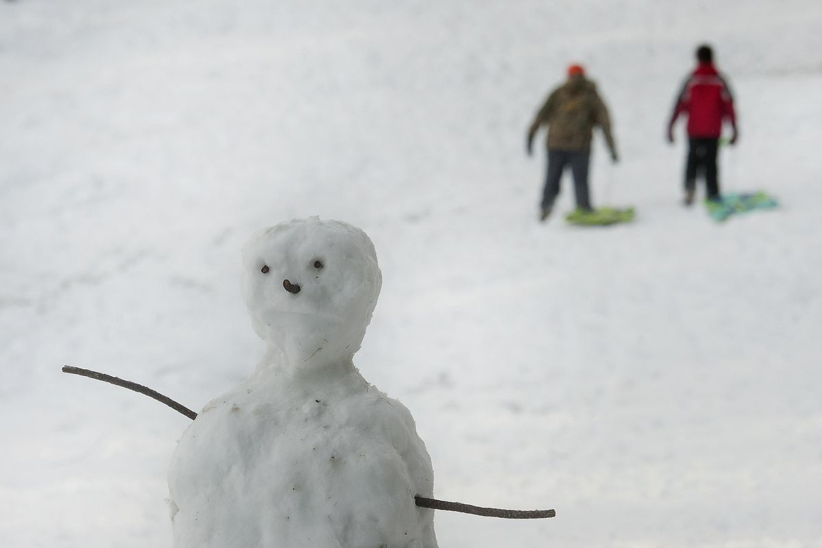 A snowman overlooks sledders at Cherry Hill Park in Coeur d