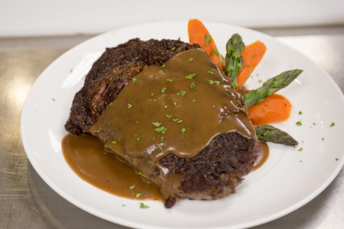 Executive banquet chef Adam Swedberg pours a classic espagnole sauce, one of the five French mother sauces, over a seared ribeye steak to demonstrate the use of the sauce in May at the Davenport Hotel. (Jesse Tinsley / The Spokesman-Review)