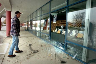 
Keith Siegwald looks at the shattered window of an empty storefront Tuesday at the Post Falls Factory Outlets. 
 (Jesse Tinsley / The Spokesman-Review)