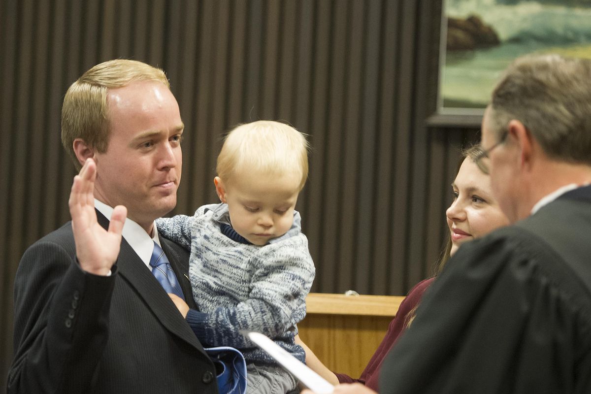 FILE – Josh Kerns, holds his son Joey as his wife Nichole looks on as Judge Richard Leland swears him in as Spokane County commissioner on Nov. 29, 2016, at the Spokane County Public Safety Building in Spokane, Wash. (Tyler Tjomsland / The Spokesman-Review)