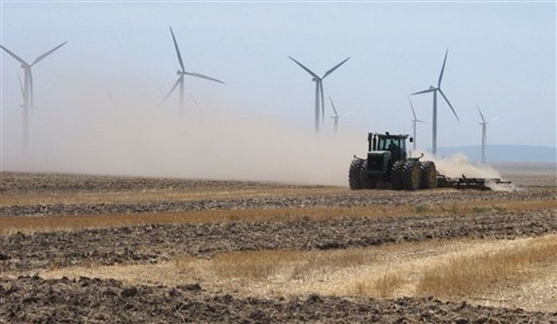A farmer plows a field near wind turbines owned by Chicago-based Exelon Corp. outside of Mountain Home, Idaho on Thursday, Aug. 2, 2012. State electricity regulators aiming to set the course for Idaho's renewables industry for years to come will hold hearings next week on long-running and bitter disputes between utilities like Idaho Power Co. and independent wind, solar and biogas developers. The Idaho Public Utilities Commission has scheduled three days of hearings starting Tuesday, to be attended by a crowd of lawyers, utility executives and environmentalists. (AP / John Miller)
