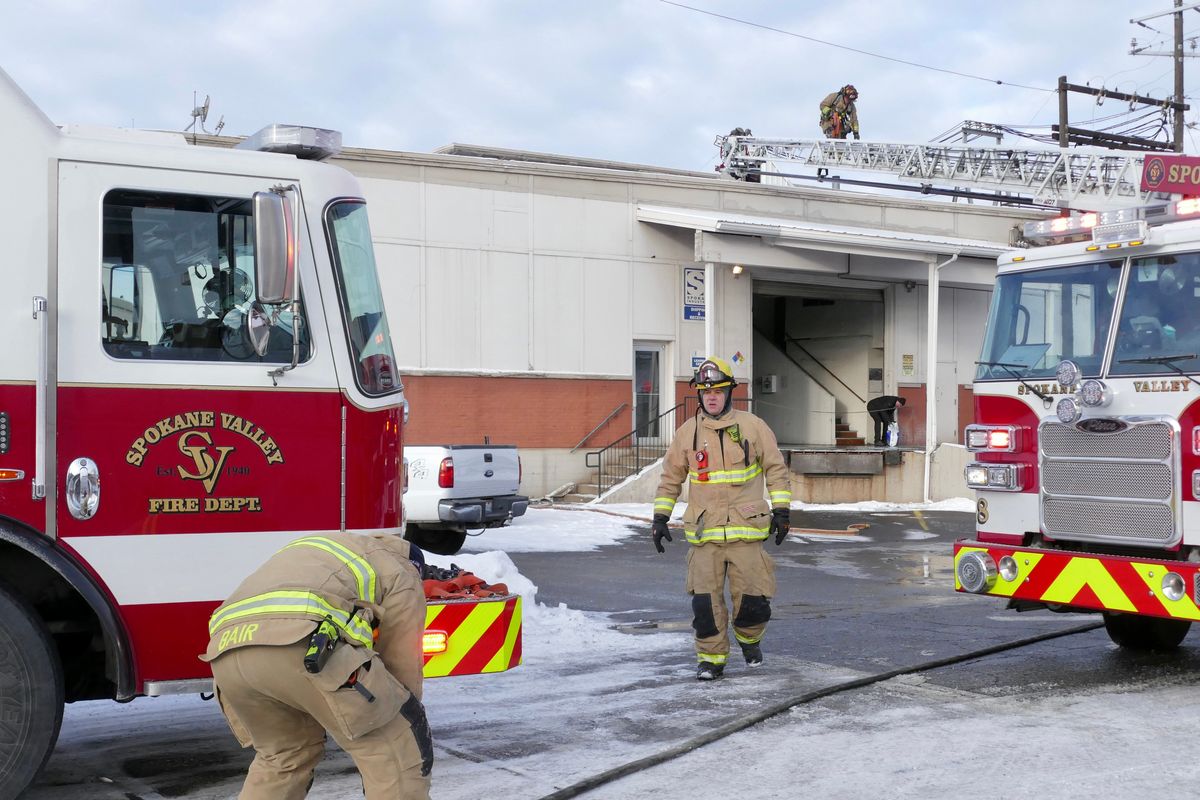 Spokane Valley firefighters roll up hose and other equipment outside a Spokane Industries foundry building in the Spokane Industrial Park Wednesday, Dec. 29, 2021 after an early morning fire.  (Jesse Tinsley/The Spokesman-Review)