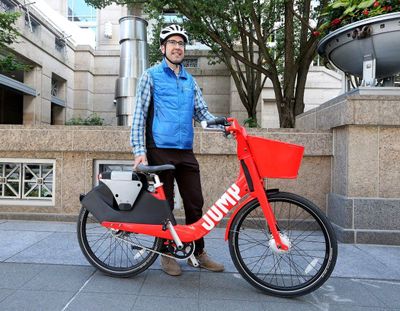 Uber spokesman Nathan Hambley shows off a bright-red electric bike from JUMP, a bike-share startup that Uber recently acquired. (Greg Gilbert / Seattle Times)