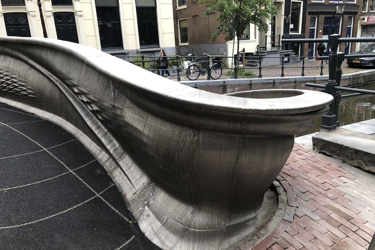 A steel 3D-printed pedestrian bridge spans a canal in the heart of the red light district in Amsterdam, Netherlands, Thursday, July 15, 2021. The distinctive flowing lines of the 12-meter (40-foot) bridge were created using a 3D printing technique called wire and arc additive manufacturing that combines robotics with welding.  (Aleksandar Furtula)