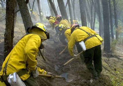 
Fire District 9 firefighters carve a line around a fire that started behind a house at 7606 W. Rutter Parkway Monday evening and burned within 50 feet of another home.
 (Colin Mulvany / The Spokesman-Review)