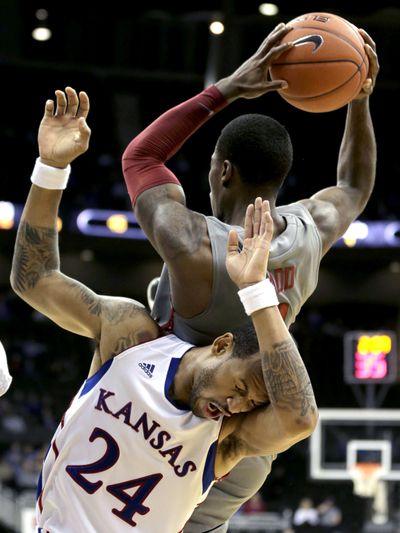 Washington State guard Mike Ladd (2) falls onto Kansas guard Travis Releford (24) after pulling down a rebound during the first half of an NCAA college basketball game Monday in Kansas City, Mo.  (Associated Press)