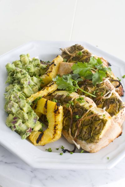 Cooking chicken or salmon between slabs of pineapple rind imparts sweetness and keeps it moist. Pineapple Bark Chicken with Grilled Pineapple and Guacamole is shown here. (Associated Press)