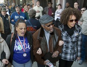 FILE - In this Friday, March 6, 2015, file photo, from left, Della Montgomery-Riggins, Charles Thornton and Spokane NAACP president Rachel Dolezal link arms and sing "We Shall Overcome" at a rally in downtown Spokane, Wash., responding to a racist and threatening package received by Dolezal. Dolezal is now facing questions about whether she lied about her racial identity, with her family saying she is white but has portrayed herself as black. (Dan Pelle/The Spokesman-Review via AP, File) (Dan Pelle / The Spokesman-Review)