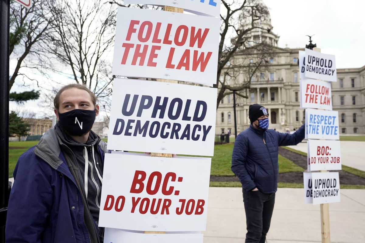 Joscha Weese, left, stands outside the Capitol building during a rally in Lansing, Mich., Saturday, Nov. 14, 2020. Michigan