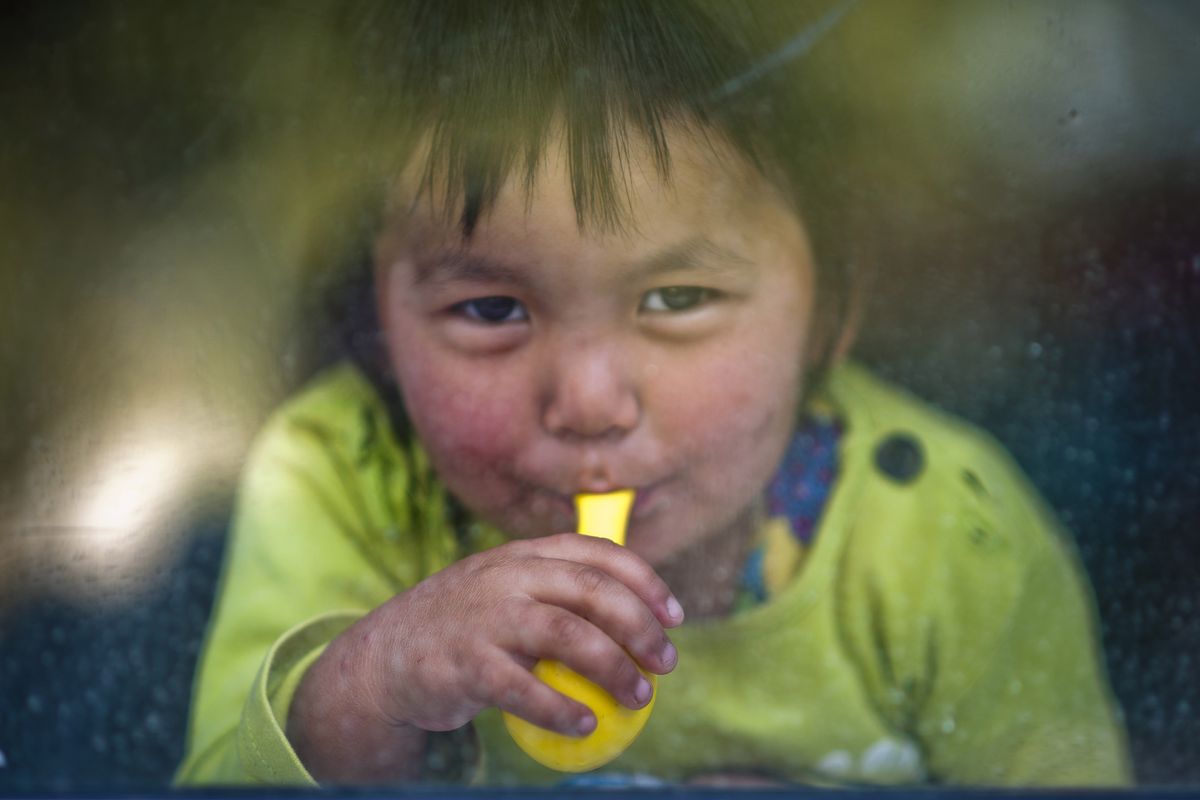 A child at the Solnyshko preschool in Vasilievka, Kyrgyzstan, watches from a classroom window as airmen from the 92nd Air Refueling Wing make a humanitarian visit at the school Monday. The children each received a winter coat, balloons, stuffed animals and school supplies. 