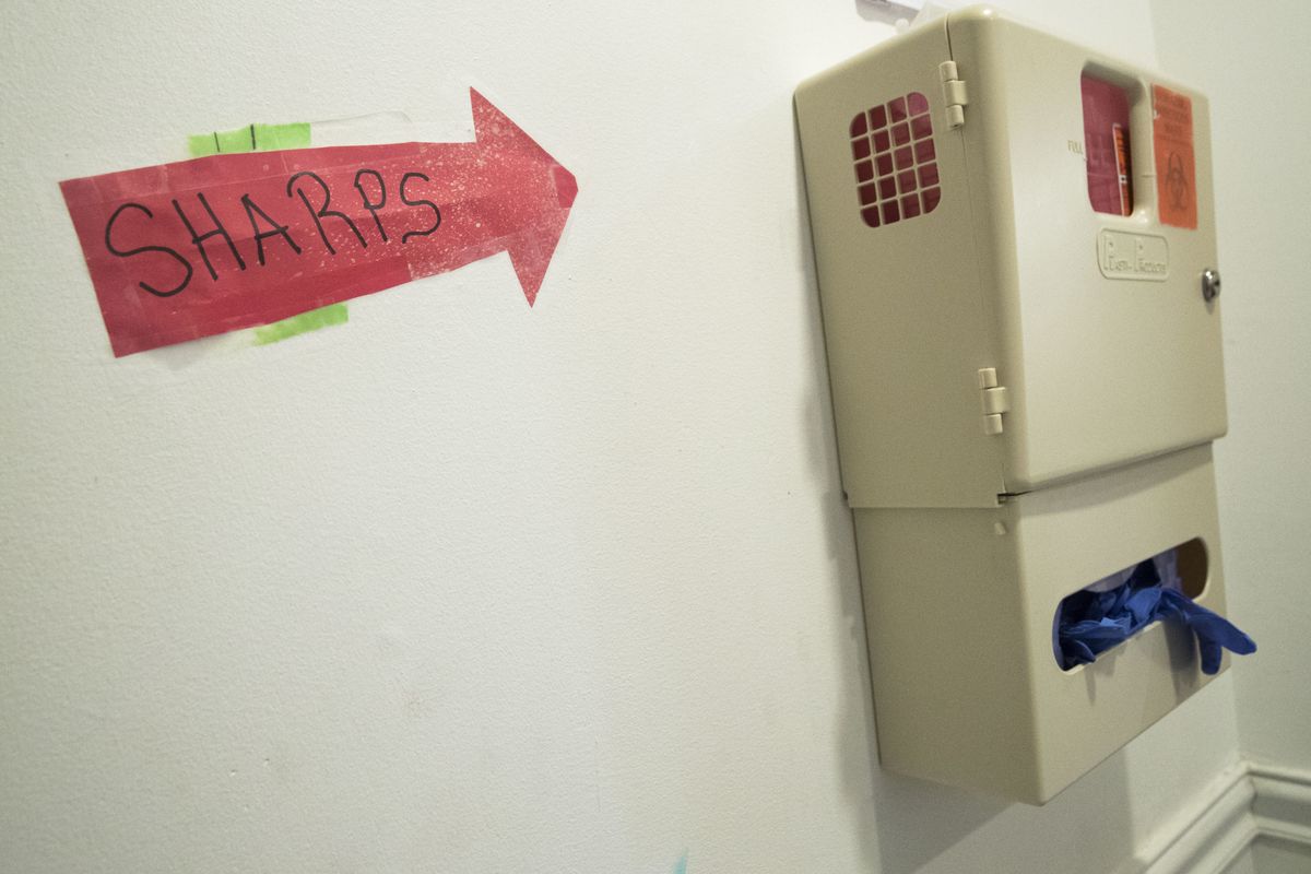 In this June 19, 2018, photo, a safe needle disposal container hangs in the bathroom of VOCAL-NY headquarters in the Brooklyn borough of New York. The first officially authorized safe havens for people to use heroin and other narcotics have been cleared to open in New York City in hopes of curbing overdoses, the mayor and health commissioner said Tuesday, Nov. 30, 2021.  (Mary Altaffer)
