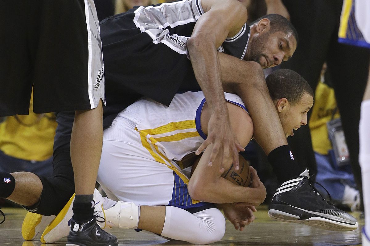 Golden State Warriors guard Stephen Curry, bottom, tries to control the ball below San Antonio Spurs forward Tim Duncan. (Associated Press)