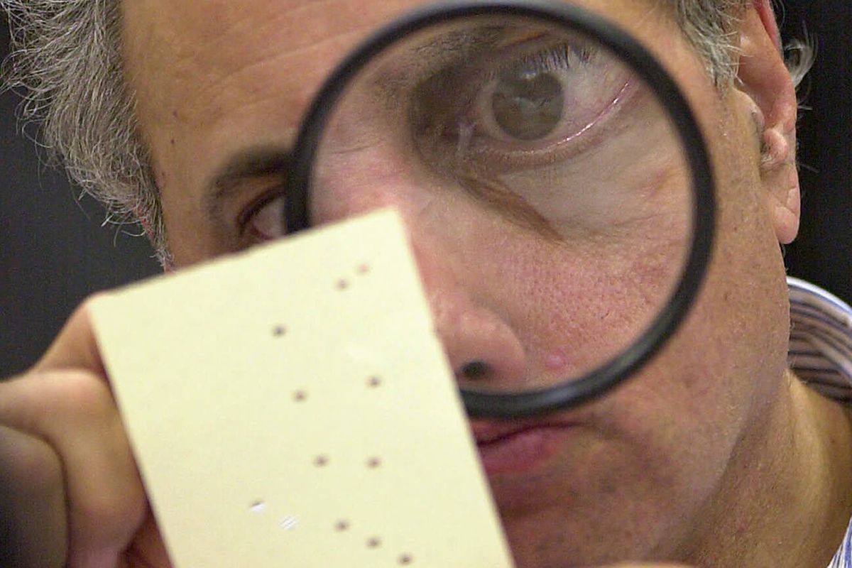 FILE - This Nov. 24, 2000 file photo shows Broward County canvassing board member Judge Robert Rosenberg using a magnifying glass to examine a disputed ballot at the Broward County Courthouse in Fort Lauderdale, Fla. Twenty years ago, in a different time and under far different circumstances than today, it took five weeks of Florida recounts and court battles before Republican George W. Bush prevailed over Democrat Al Gore by 537 votes.  (ALAN DIAZ)