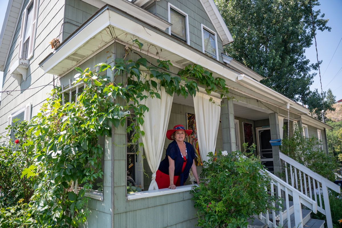 Owner Mary Moltke stands on the porch of the house at 301 N. Cedar Street in Peaceful Valley Tuesday, July 11, 2023. The house was featured in the movie "Benny and Joon" which was filmed in Spokane in 1993, thirty years ago. The house is one of the few homes that backs up to the Spokane River.  (Jesse Tinsley/THE SPOKESMAN-REVI)