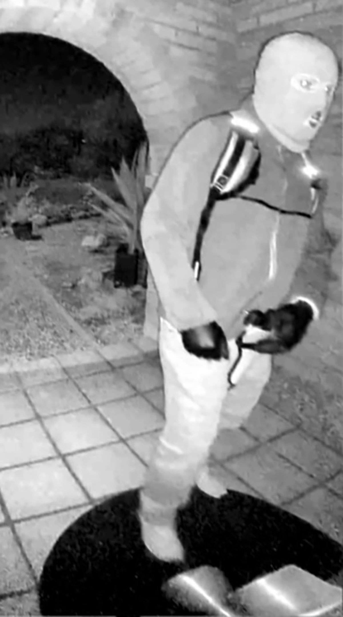 The image shows an armed individual appearing to have tampered with the camera at Nancy Guthrie