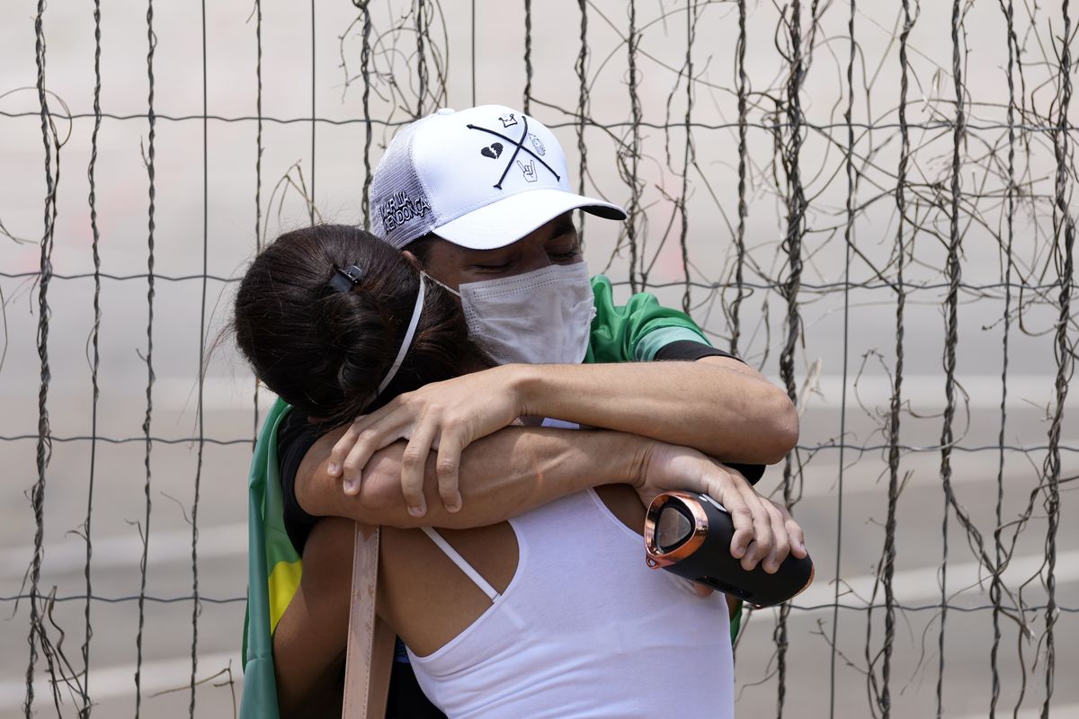 Two people hug each other as fans wait in line for access to the wake of Brazilian singer Marilia Mendonca, in front of the Ginasio Arena in the city of Goiania, Brazil, Saturday, Nov. 6, 2021. One of Brazil