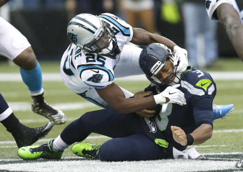 Seattle Seahawks quarterback Russell Wilson, right, is tackled by Carolina Panthers cornerback Bene' Benwikere after Wilson rushed for a gain in the first half of an NFL football game, Sunday, Oct. 18, 2015, in Seattle. (Stephen Brashear / AP)