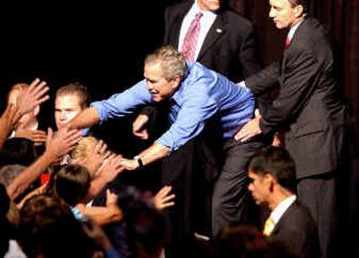 
President Bush is held by members of his Secret Service staff as he reaches into the crowd while shaking hands with supporters following a rally at the Family Arena in St. Charles, Mo. Tuesday. 
 (Associated Press / The Spokesman-Review)