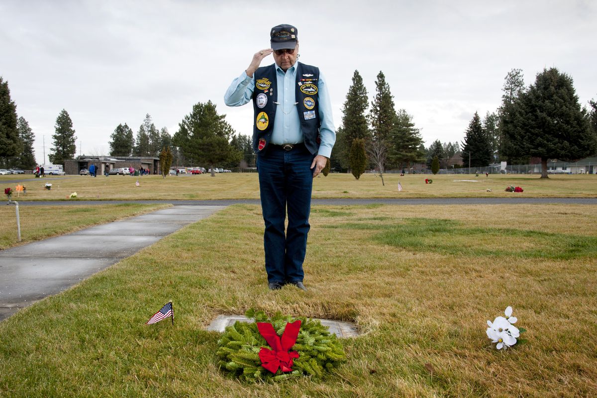 After placing a wreath, Mike McGill salutes the grave of fellow U.S Navy veteran Charles Dale Fredericks during the Wreaths Across America Day ceremony at Pines Cemetery in Spokane Valley on Saturday. (PHOTOS BY DAN PELLE)