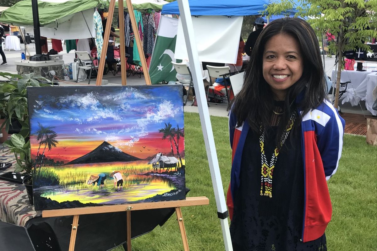Artist Abrelli Firestone is pictured in Spokane Valley Saturday with one of her paintings featuring Mount Mayon in the Philippines. {span} {/span}  (Nina Culver for The Spokesman-Review)