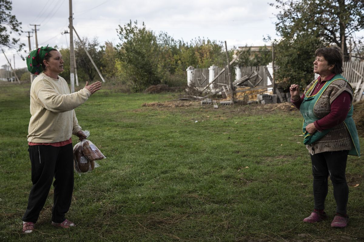 Olga Prodchenko, 45, left, argues with her neighbor, Halyna Pylypenko, 62, who refuses to accept bread Olga tried to give her, calling it "Russian bread" and accusing her of collaborating with Russian forces when the village was under occupation for more than six months.    (Heidi Levine/For The Washington Post)