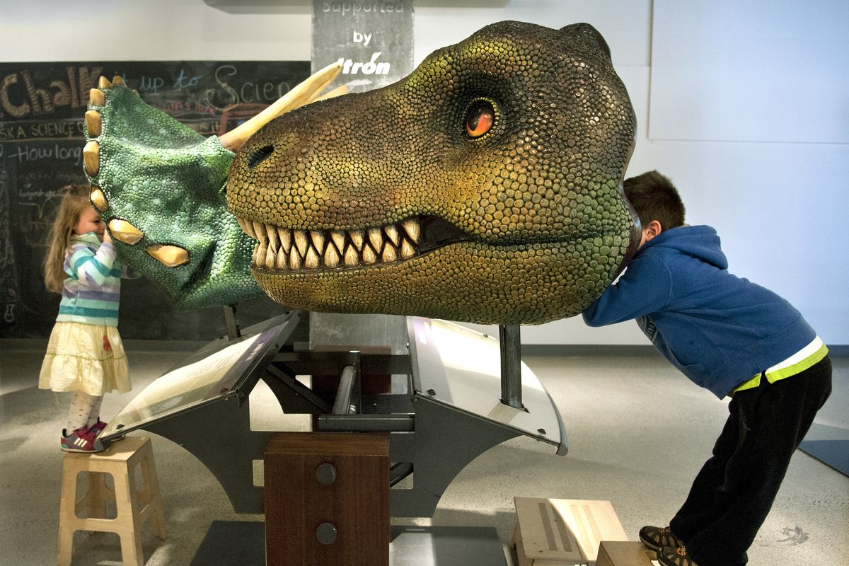 Thor Tenold, 5, right, looking through a Tyrannosaurus rex interactive exhibit, and his sister Ada, 3, looking through a triceratops head, see from a dinosaur’s point of view as they visit the “T. Rex Named Sue” exhibit in September at Mobius Science Center in downtown Spokane. (File)