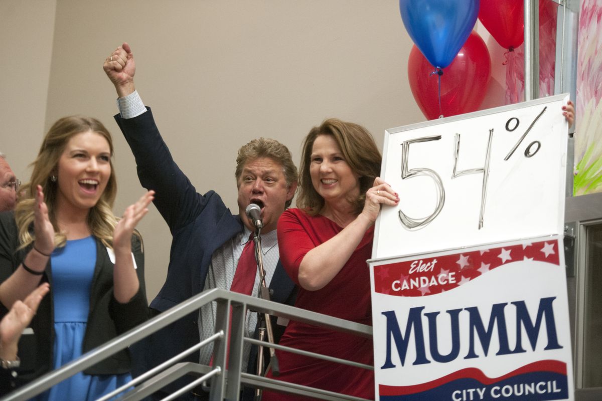 Spokane City Council Candidate Candace Mumm, right, holds up a whiteboard with her percentage of the vote just after it was announced, and celebrates with her husband, Steve Mumm, second from left, and other family members at the Central Food building in Kendall Yards on Tuesday. (Jesse Tinsley)