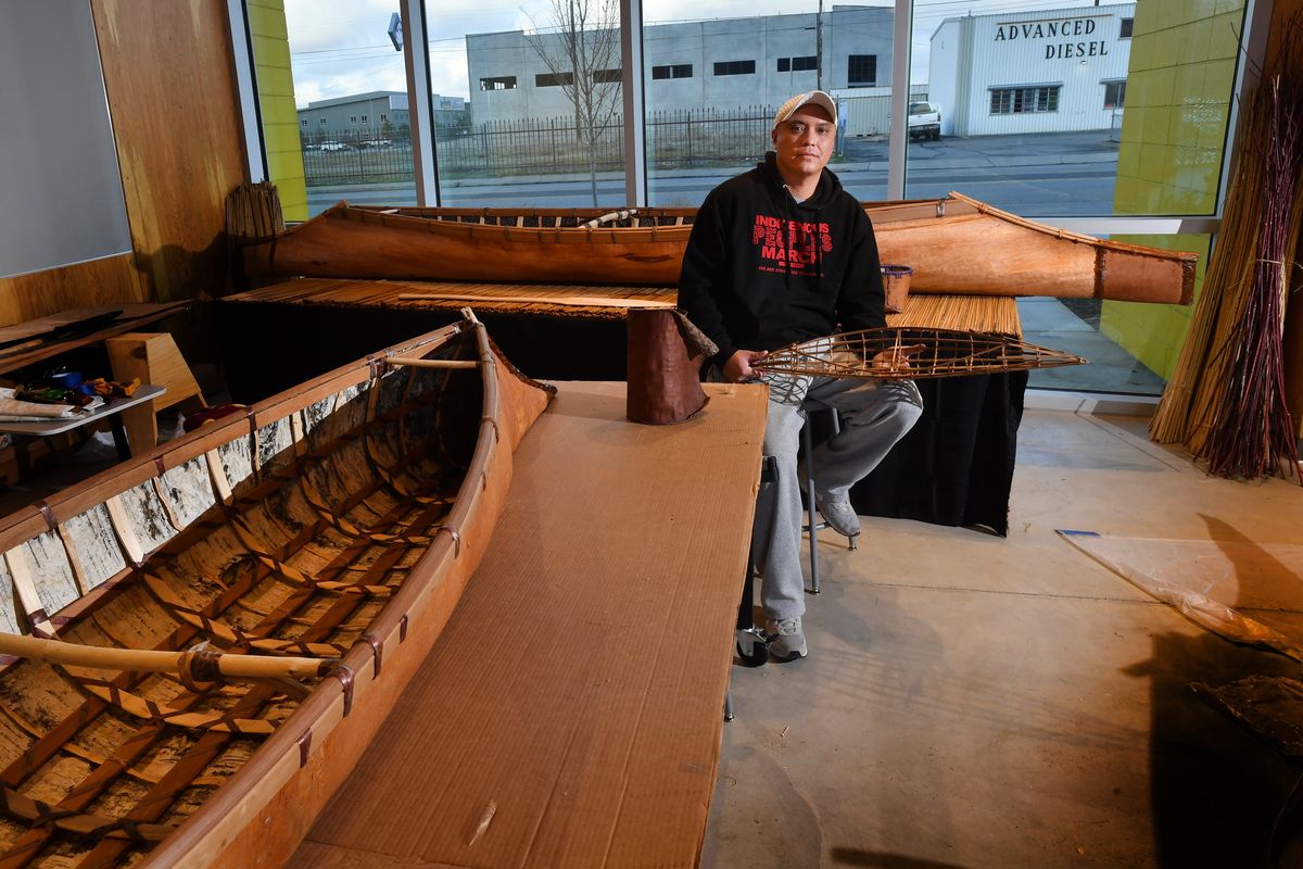 ABOVE: Artist-in-residence Shawn Brigman poses for a photo with two ancestral sturgeon-nose canoes on Tuesday, Dec 14, 2021, at The Hive in Spokane, Wash. LEFT: A traditionally made Salishan Sturgeon Nose Canoe. The canoe is 16 feet long and weighs about 40 pounds.  (Tyler Tjomsland/The Spokesman-Review)