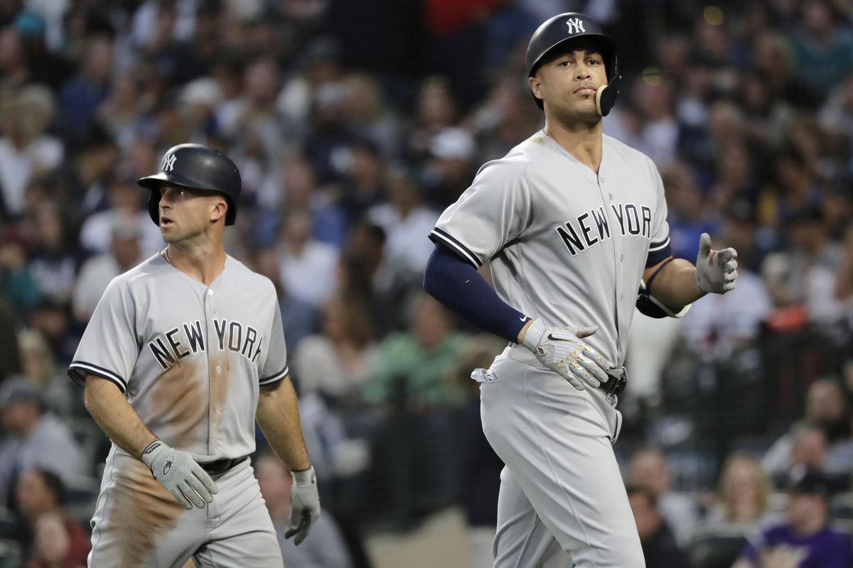 New York Yankees’ Brett Gardner, left, and Giancarlo Stanton walk to the dugout after Gardner scored on a sacrifice fly by Stanton during the fifth inning against the Seattle Mariners on Saturday in Seattle. (Ted S. Warren / AP)