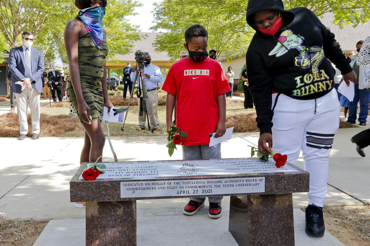 Jasmyne Smith, Kaiden Hutchins and Erick Thomas lay roses Tuesday in memory of loved ones killed in the 2011 tornado that struck Rosedale Court, a public housing development, in Tuscaloosa, Ala.  (Gary Cosby)