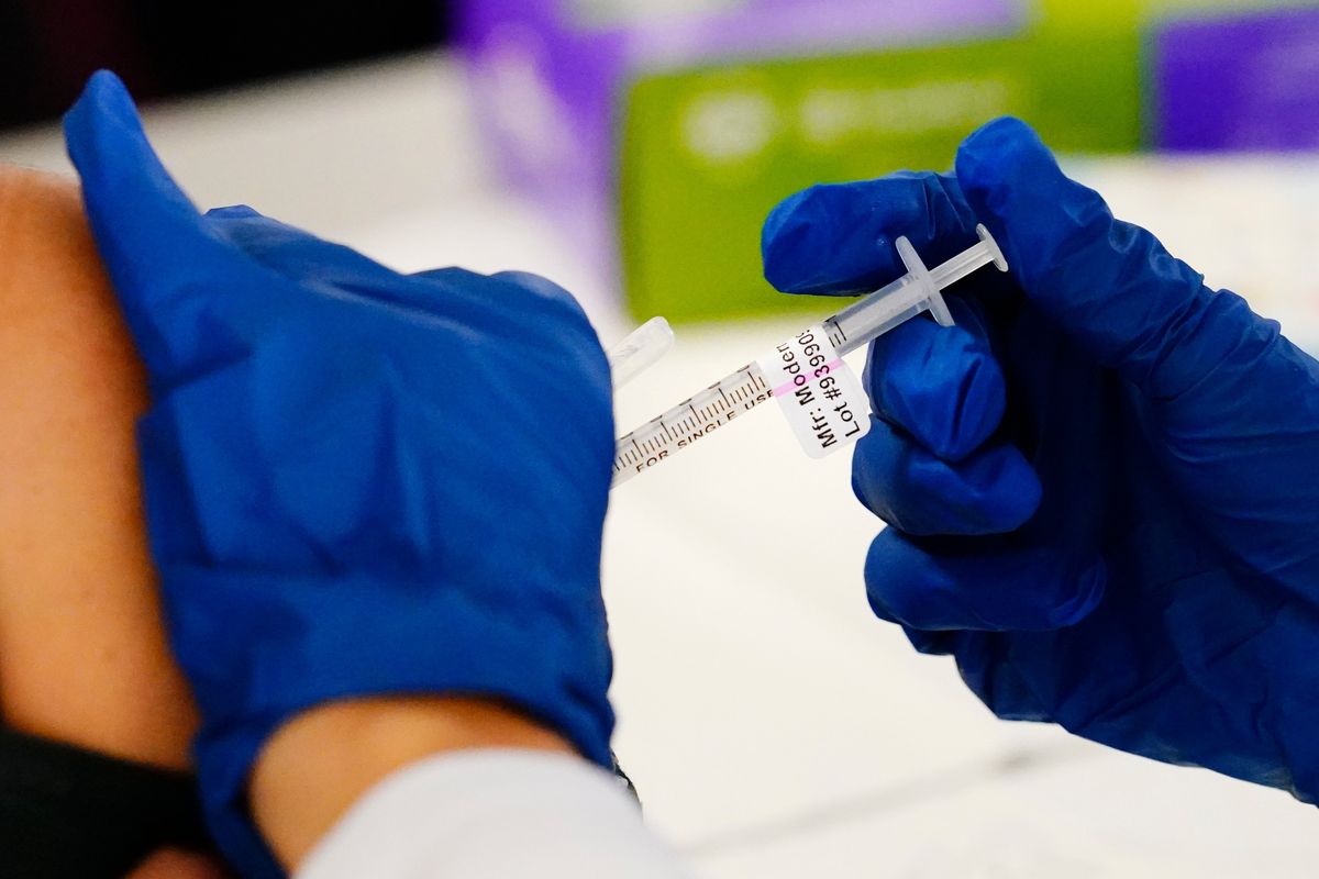 FILE - A health worker administers a dose of a Moderna COVID-19 vaccine during a vaccination clinic at the Norristown Public Health Center in Norristown, Pa., Tuesday, Dec. 7, 2021. The Centers for Disease Control and Prevention posted revised guidelines on Thursday, Dec. 23, that are loosening rules that call on health care workers to stay out of work for 10 days if they test positive for COVID-19. Those workers will be allowed to come back to work after seven days if they test negative and don’t have symptoms.  (Matt Rourke)