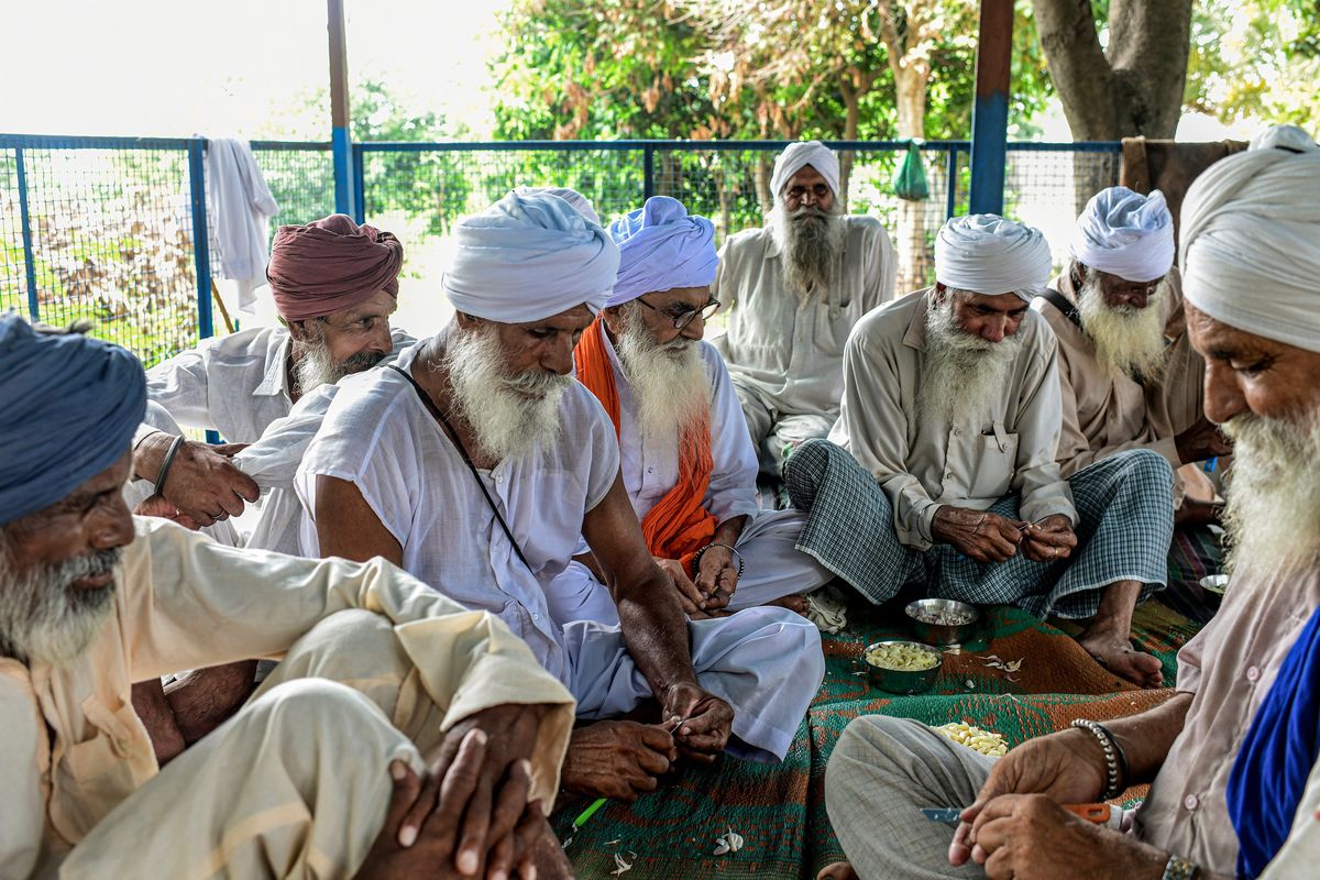 Karnail Singh Kakkar, in orange, with his friends at a village temple in Kakkar, India, on Aug. 7. A village in northern India has found a way to address a growing global issue: a deep sense of isolation among older people. (ATUL LOKE)
