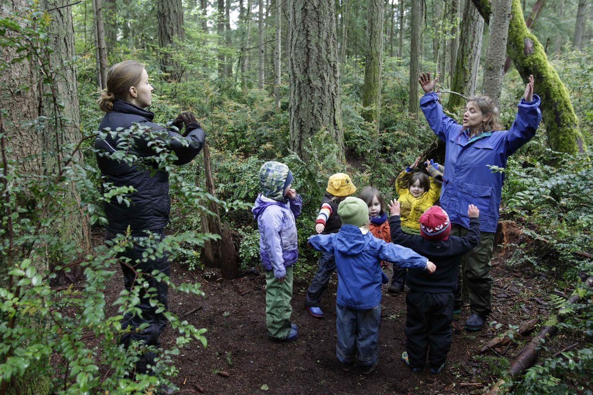 Teachers Karen Olsen, left, and Erin Kenny  lead children in song at  Cedarsong Nature School. Associated Press photos (Associated Press photos)