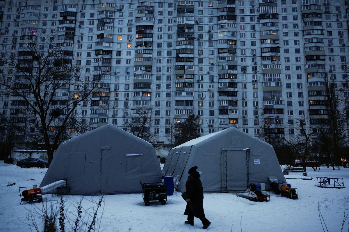 A person walks past a Point of Invincibility center, a government‑run shelter that provides basic services and heat during blackouts, set up next to an apartment building left without heating and facing long power cuts after critical civil infrastructure was hit by recent Russian missile and drone strikes, amid Russia’s attack on Ukraine on Friday, in Kyiv.   (Reuters )