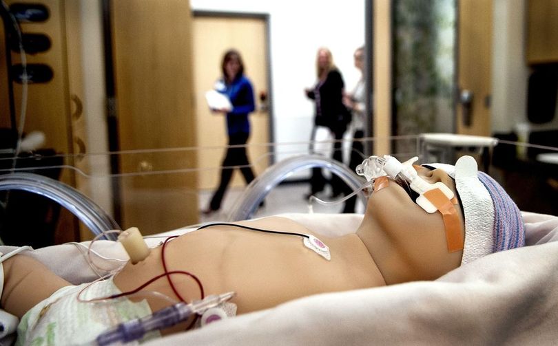 A tour guide leads a group past the expanded neonatal intensive care unit in Kootenai Health’s $57 million east addition in Coeur d’Alene on Thursday. Dolls were used to show how the equipment would be used when the new family birth center opens this month. (Kathy Plonka / The Spokesman-Review)