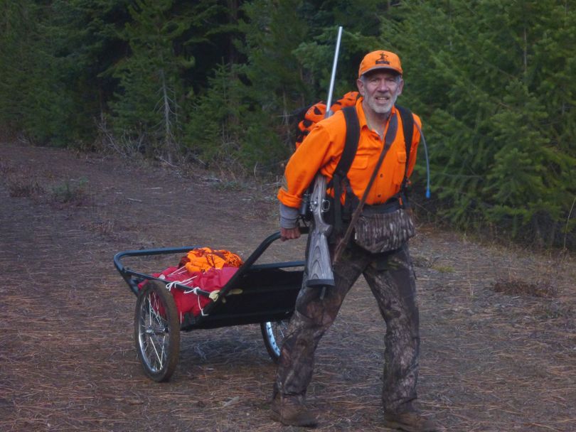 On the sixth day of hunting, after 8 hours of field dressing, skinning and then deboning and packing the meat of my cow elk out of a canyon, Outdoors editor Rich Landers enjoys the relatively easy last two miles of hiking back to camp with the help of a cart and his hunting partner, Jim Kujala. (Jim Kujala)