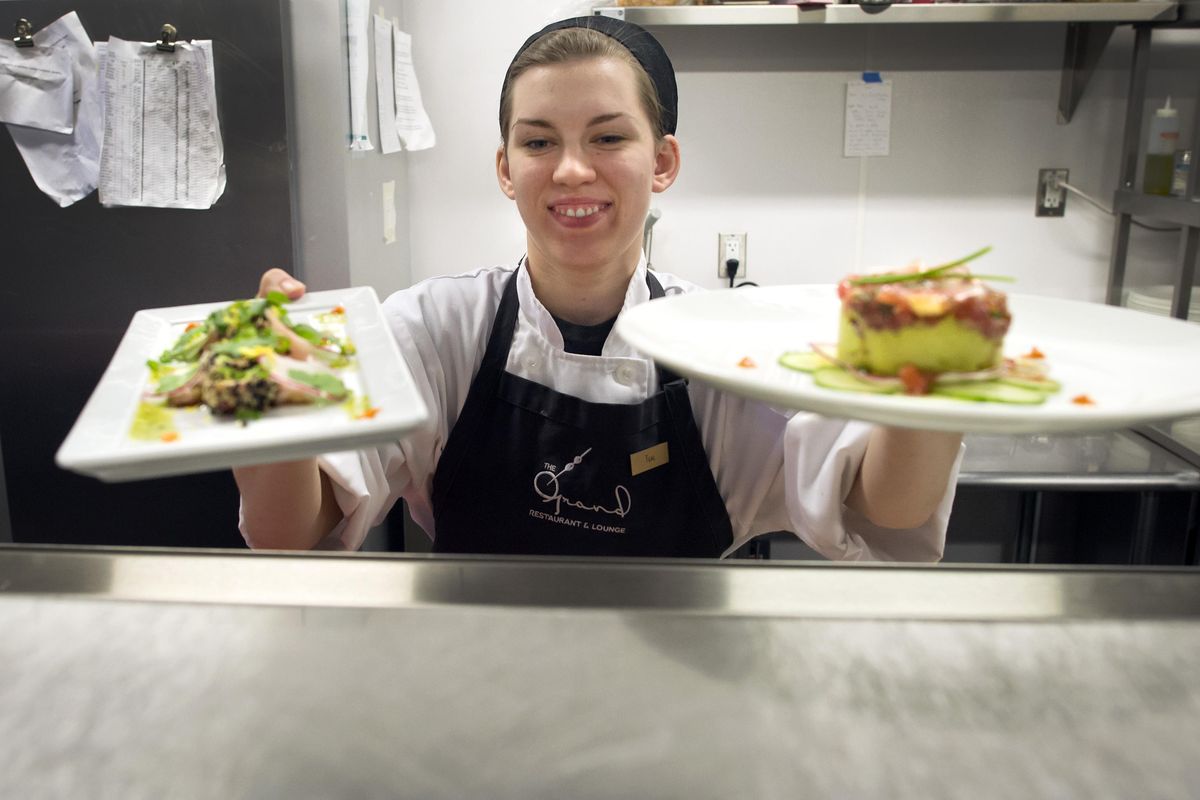 Teal Delys, a cook for the The Grand Restaurant and Lounge, prepares plates of Asian Ahi, left and Ahi Pokes, Wed., Dec. 30, 2015, in the hotel kitchen. The Davenport Grand Hotel is a big new employer in the local leisure and hospitality industry. (Colin Mulvany / The Spokesman-Review)