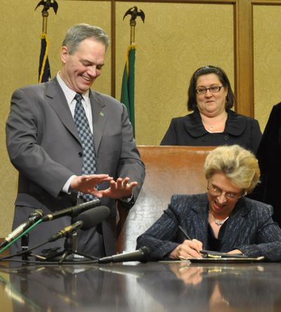 As Gov. Chris Gregoire signs the supplemental budget from the special legislative session, Rep. Ross Hunter, D-Medina, chairman of the House budget committee, looks on. (Jim Camden)