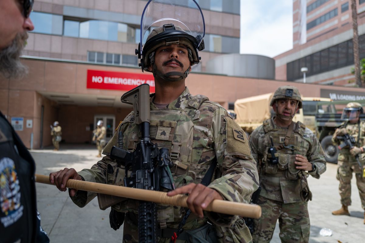 National Guard soldiers stand alongside federal officers as protesters gather outside the Metropolitan Detention Center on Sunday in Los Angeles. (Spencer Platt)