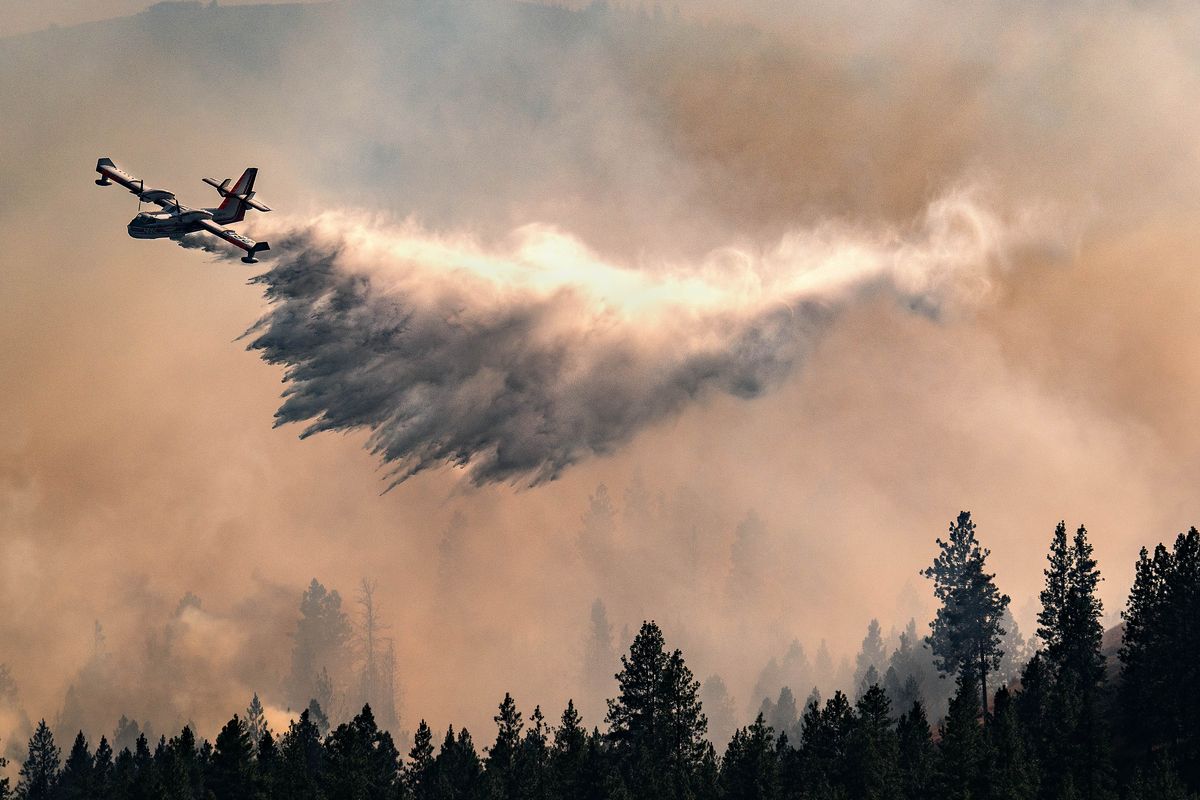 A firefighting aircraft drops water on a fast-moving brush fire near the Eagle Ridge housing development in 2023. (COLIN MULVANY/THE SPOKESMAN-REVI)