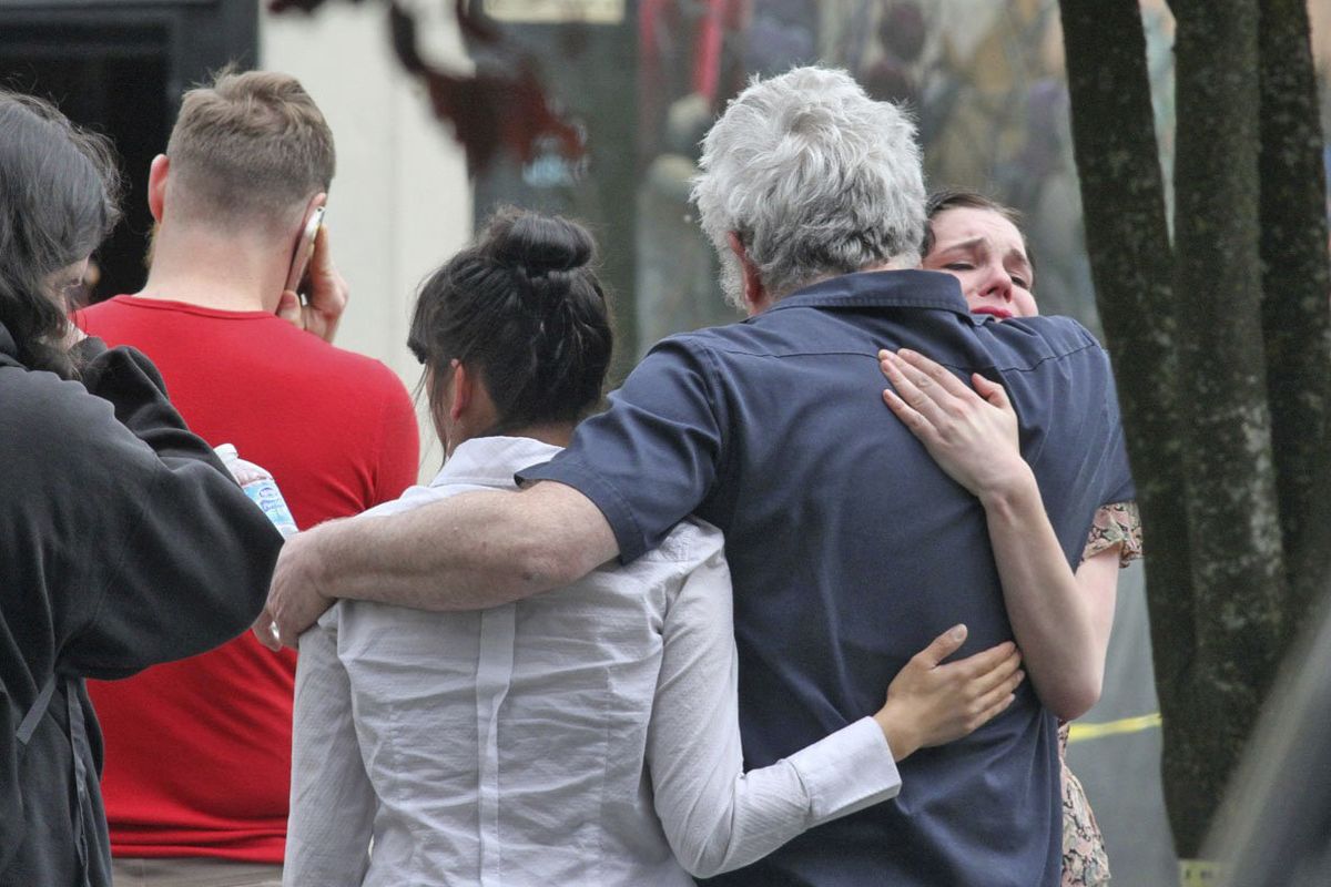 People console each other outside Cafe Racer in Seattle, where a gunman killed four people and wounded another Wednesday. (Associated Press)