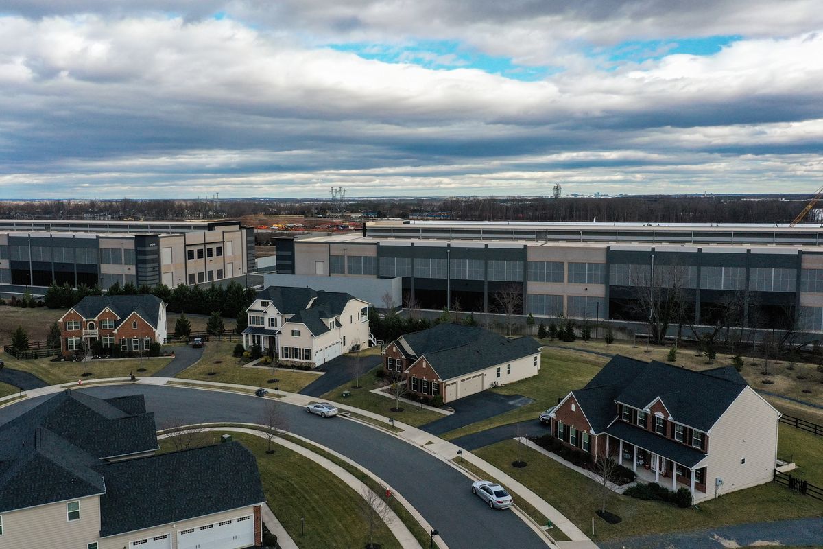 Built on what was recently farmland, Amazon data centers loom over houses at the edge of the Loudoun Meadows neighborhood on January 20, 2023, in Aldie, Va. As the data center industry expands its footprint in Northern Virginia, often building massive commercial structures near residential neighborhoods, communities push back with their concerns.  (Jahi Chikwendiu/Washington Post)