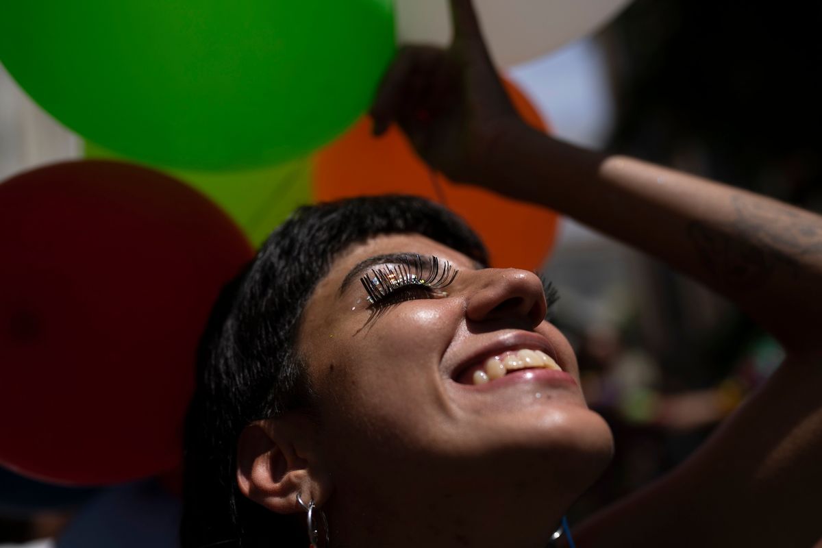 A reveler smiles during an unofficial carnival block party referred to as "blocos", in Rio de Janeiro, Brazil, Saturday, Feb. 26, 2022. City Hall banned all blocos, the tightly packed street parties attended by those who cannot or don