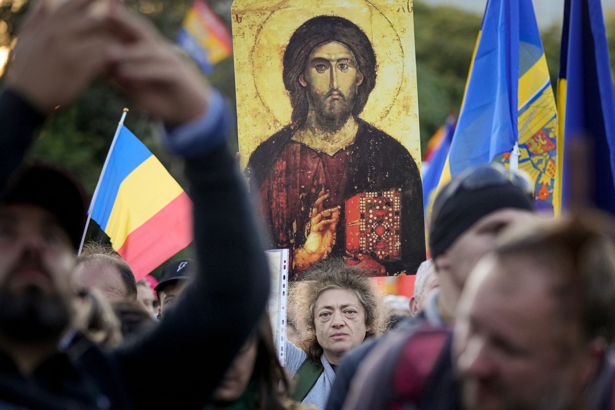 A woman holds an icon during an anti-government and anti-vaccination protest organised by the far-right Alliance for the Unity of Romanians or AUR, in Bucharest, Romania, Saturday, Oct. 2, 2021. Thousands took to the streets calling for the government