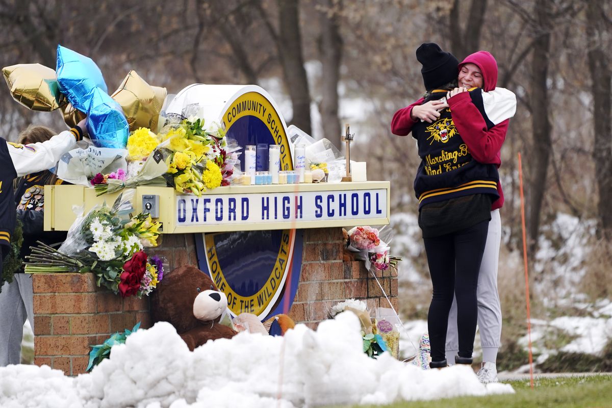 Students hug at a memorial at Oxford High School in Oxford, Mich., Dec. 1, 2021. School systems nationwide rely on high-level expertise from the U.S. Secret Service and others as they work to stay vigilant for signs of potential student violence, training staff, surveilling social media and urging others to tip them off. However, when it comes to deciding how to respond to a possible threat, it’s the local educators who make the call.  (Paul Sancya)